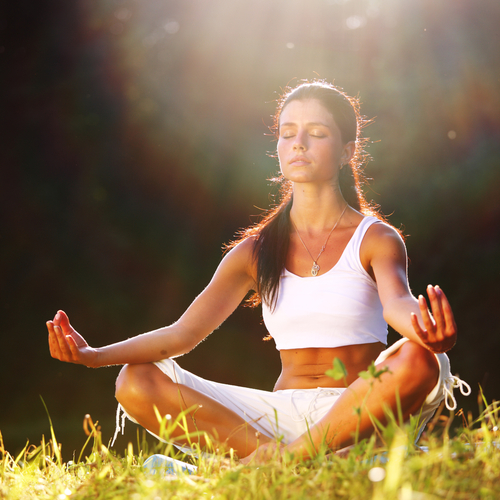 woman meditating in the grass